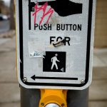 An image of a vandalized pedestrian crossing button.
